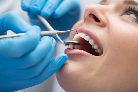 examining a patient's teeth in the dentist office