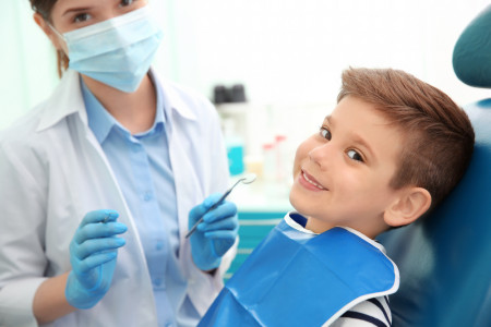 examining boy's teeth in dental clinic