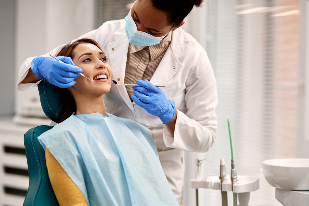 African,American,Dentist,Examining,Teeth,Of,Her,Female,Patient,During